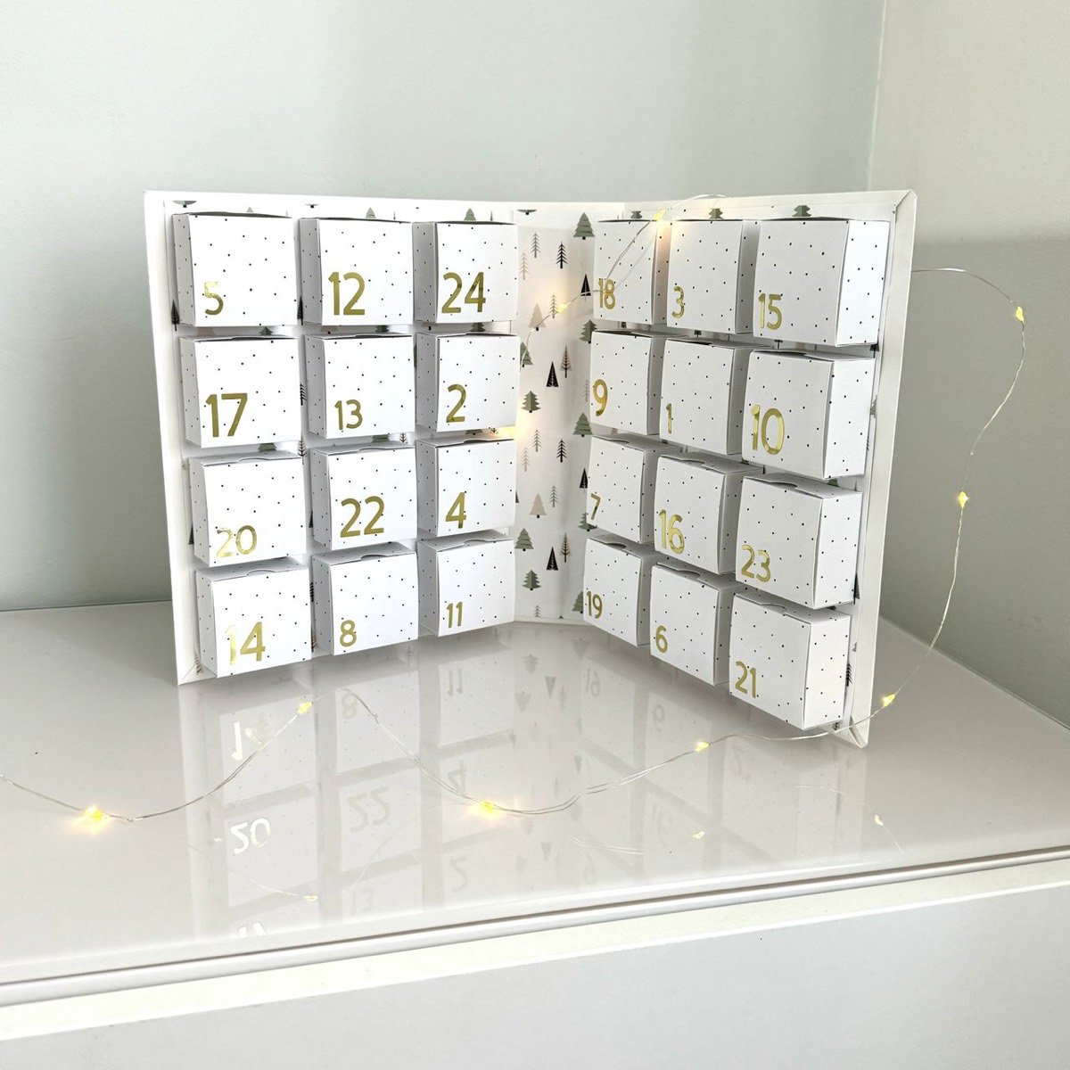 Calendrier de l’Avent Cricut en forme de livre ouvert contenant 24 boîtes